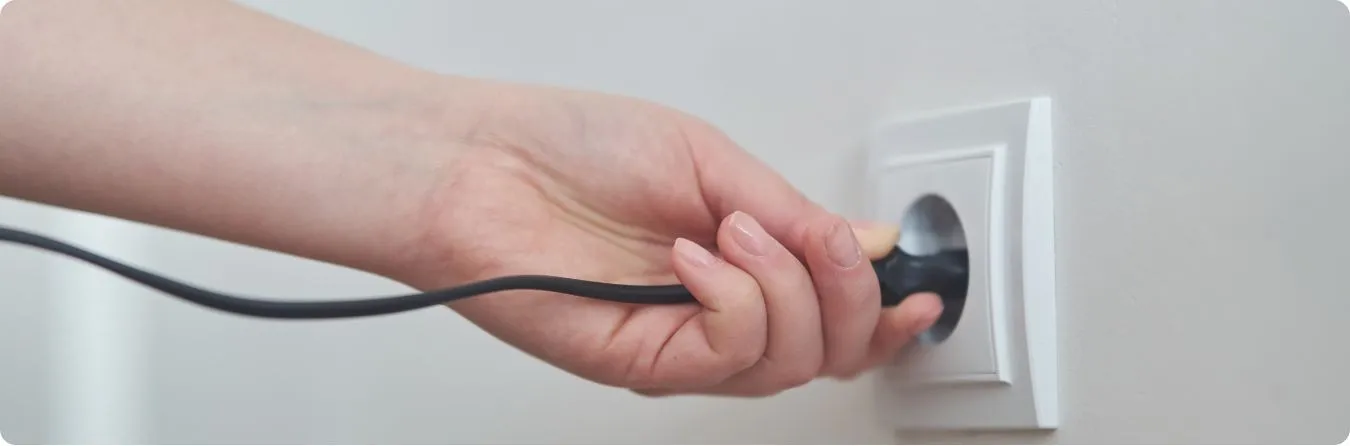 Frau die einen Stecker in eine Steckdose steckt.