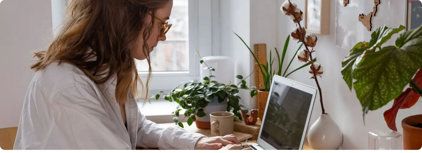 Frau die in ihrer Wohnung am Laptop sitzt und arbeitet.